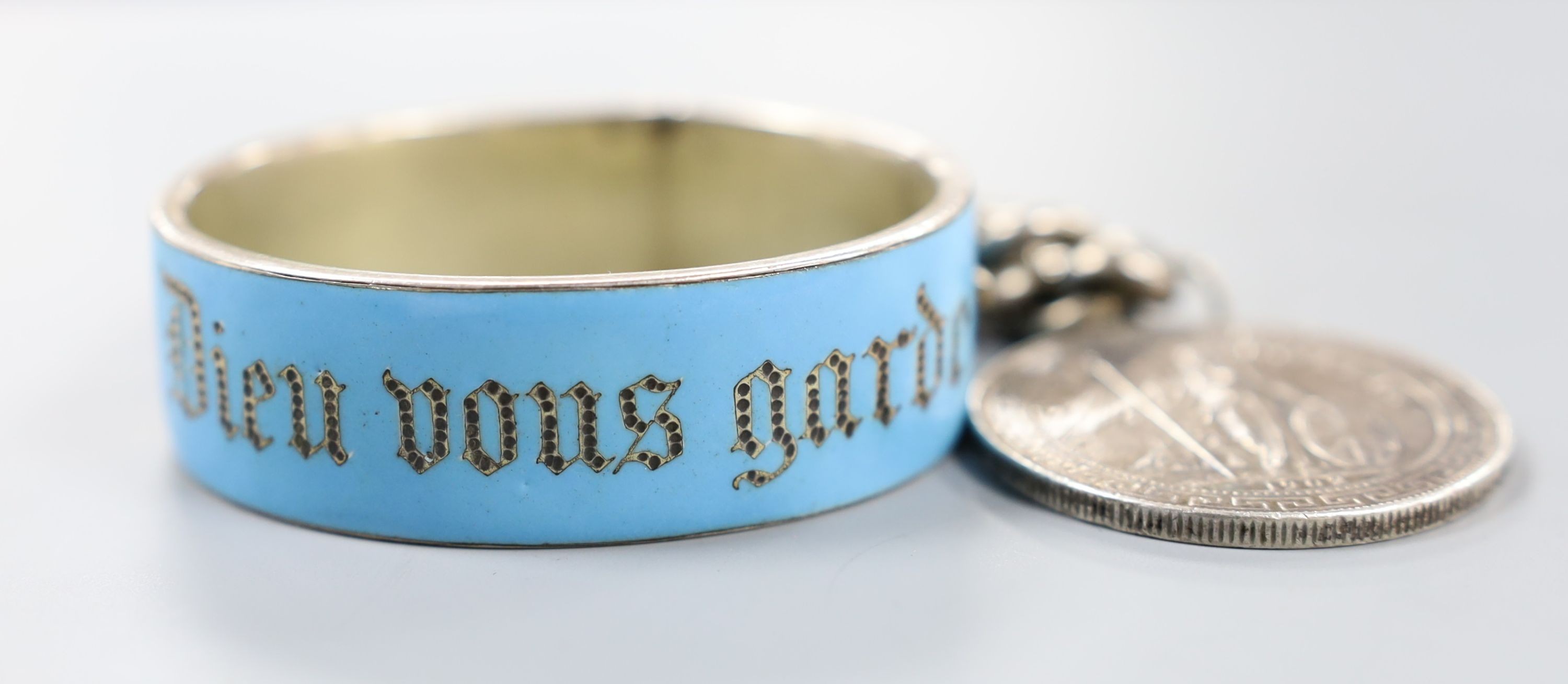 A German white metal and enamel bangle(a.f.) and an 835 white metal curb link bracelet hung with a one dollar coin.